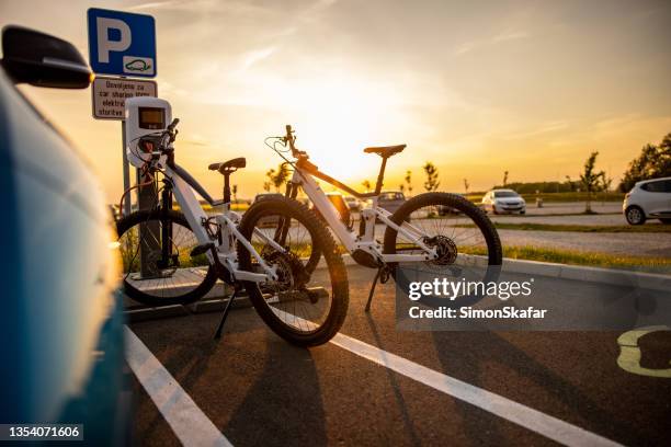 two electric bicycles being charged at the electric vehicle charging station - ebike stock pictures, royalty-free photos & images