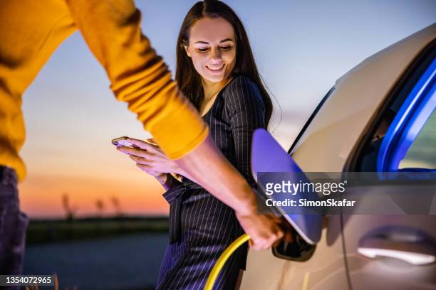 couple charging their car at night - couple in car smiling stockfoto's en -beelden