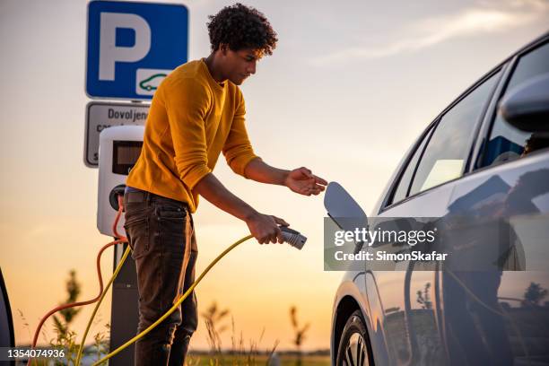 African American Man Inserting Plug Into The Electric Car Charging Socket  High-Res Stock Photo - Getty Images