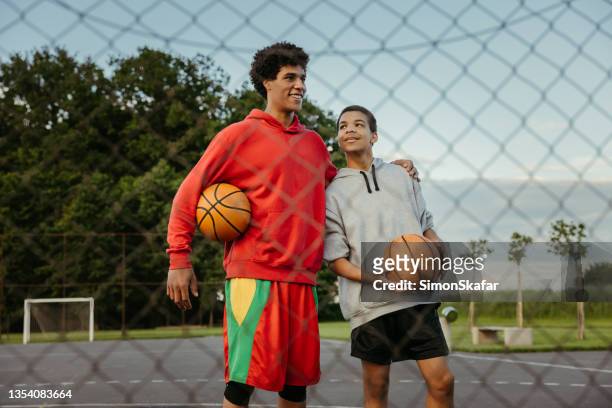 two basketball players embracing on sports court - boys basketball stock pictures, royalty-free photos & images