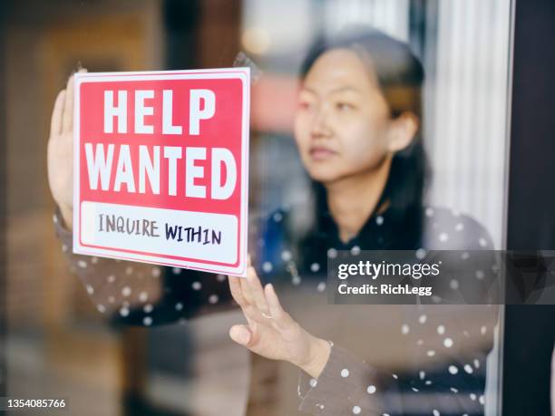 business owner putting up help wanted sign - hires stock pictures, royalty-free photos & images
