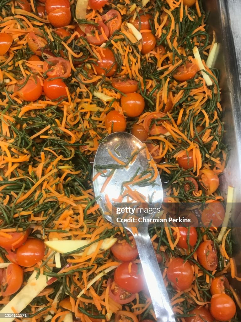 Carrot, cherry tomato, samphire and noodle salad, vegan Asian salad in salad bar, healthy fresh vegetables in canteen, vegan side dish, Asian noodle salad, spinach noodles with grated carrot and ginger dressing in London cafe in March 2020