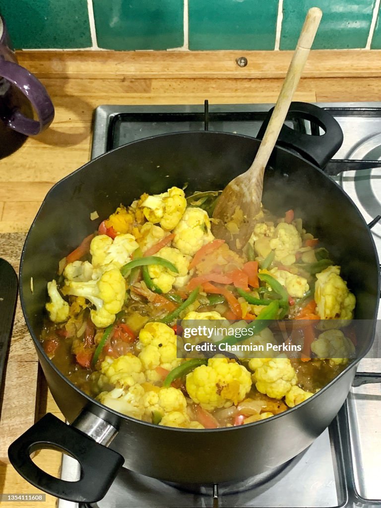 North Indian cauliflower and mixed vegetable curry, vegetable masala, kadai, gobi makhani, hot vegan curry cooking in large pot on stove, meat free and dairy free recipes from India, vegan home cooking in London home in UK in September 2021