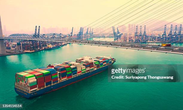 drone aerial view container cargo ship going to terminal commercial port transporting shipment container for business logistics, import export, shipping or transportation - tsing ma bridge stock-fotos und bilder