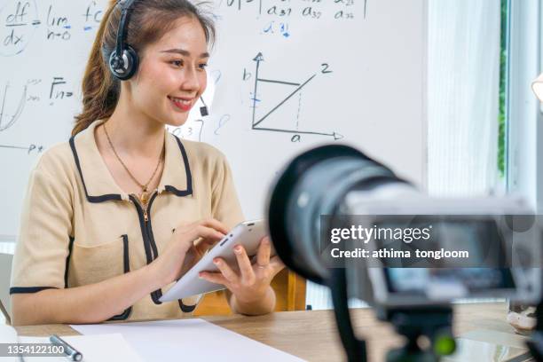 online teacher, mentor. young woman teaches and records video lessons, the camera on a tripod in front of the girl - mentoring virtual stock-fotos und bilder