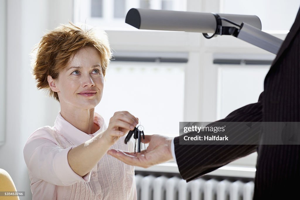 A businesswoman giving keys to a businessman