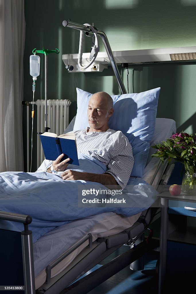 A man reading a book in a hospital bed
