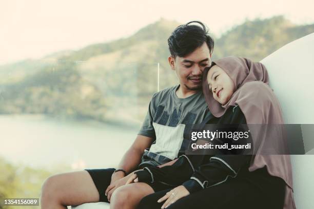 two young asian muslim couple sitting on the cafe  and looking the labuan bajo islands view on summer day - malay lover stock pictures, royalty-free photos & images
