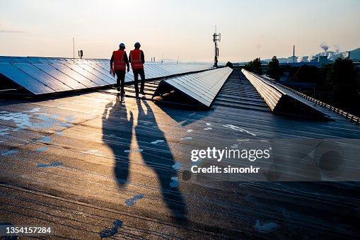 Male engineers walking along rows of photovoltaic panels Male engineers walking along rows of photovoltaic panels