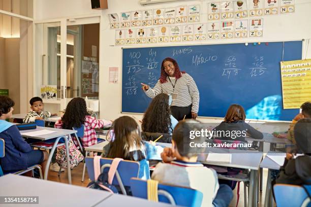 playful teacher calling on young student in arithmetic class - spanish language stock pictures, royalty-free photos & images