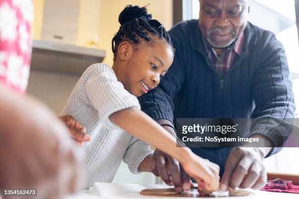 little girl making christmas gingerbread cookies with a grandparents - kids christmas lifestyle imagens e fotografias de stock