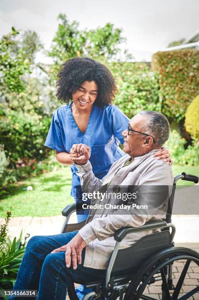foto de una atractiva joven enfermera parada afuera y ayudando a su paciente mayor en su silla de ruedas - geriatría fotografías e imágenes de stock