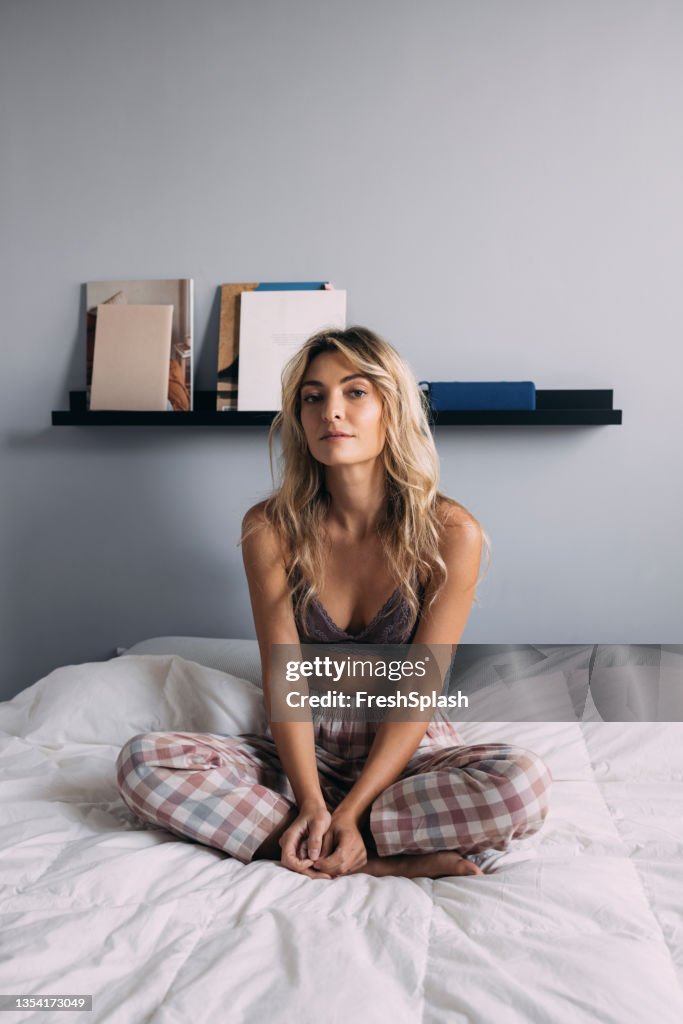 A Beautiful Female Sitting In A Lotus Position On The Bed
