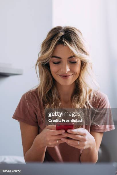 a blonde woman texting and smiling - scrolling stock pictures, royalty-free photos & images