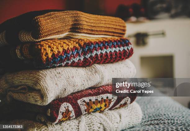 cozy fall sweaters folded and stacked up on table by window at bedroom - jersey de cuello alto fotografías e imágenes de stock