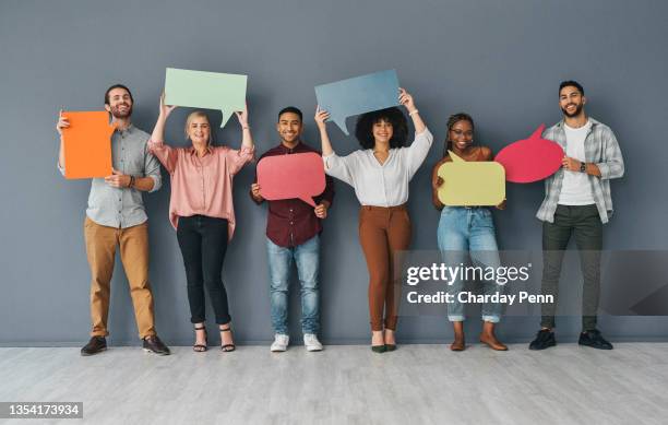 ritratto a figura intera di un gruppo giovane e diversificato di uomini d'affari che tengono cartelli vuoti a forma di bolle vocali su uno sfondo grigio in studio - tenere cartello foto e immagini stock