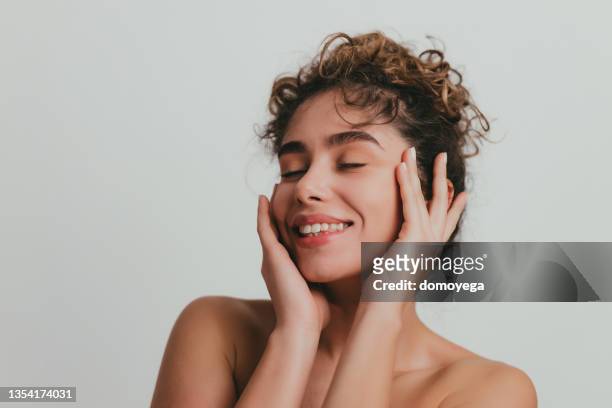 smiling young woman with curly hear and clear skin - human skin stock pictures, royalty-free photos & images
