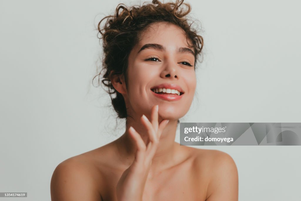 Smiling young woman with curly hear and clear skin