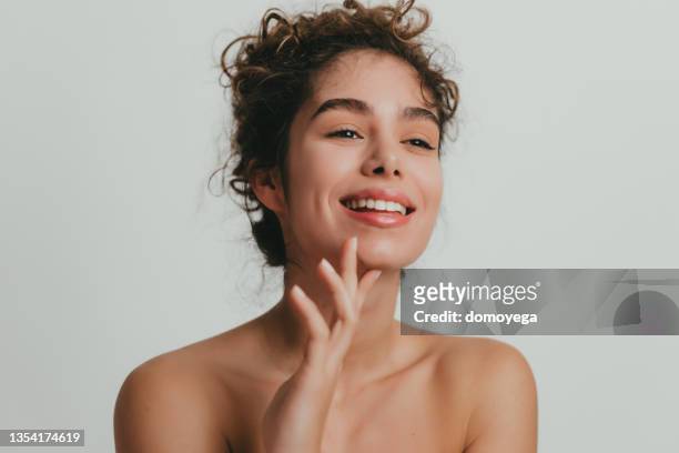 smiling young woman with curly hear and clear skin - clean beauty 個照片及圖片檔