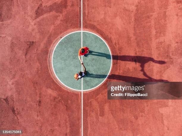 deux amis jouent au basket ensemble, se tenant la main avant le départ - point de vue aérien - round two photos et images de collection
