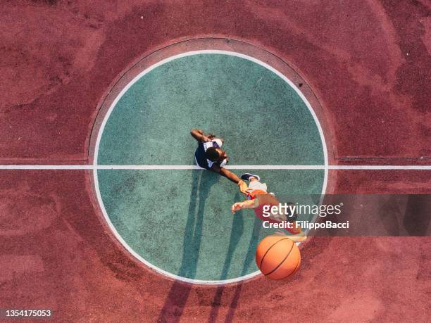zwei freunde springen, um einen basketballball auf das mittelfeld zu bringen - basketball stock-fotos und bilder