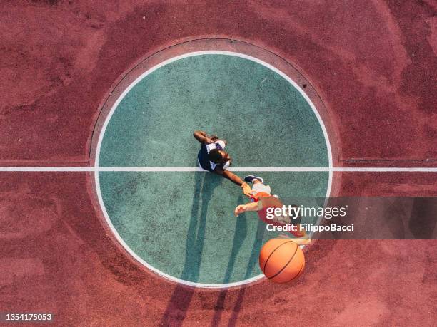 dos amigos saltan para tomar una pelota de baloncesto en el campo central - imagen de personas en movimiento fotografías e imágenes de stock
