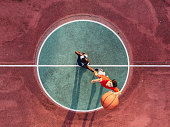 Two friends are jumping to take a basketball ball on the center field