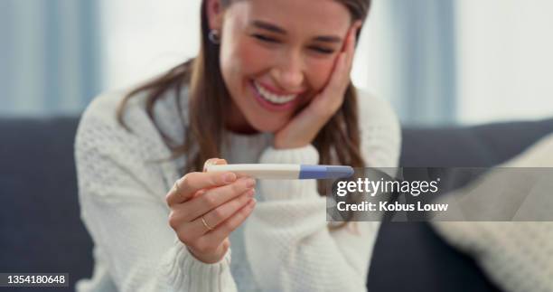 shot of a young woman looking at her pregnancy test - zwangerschapstest stockfoto's en -beelden