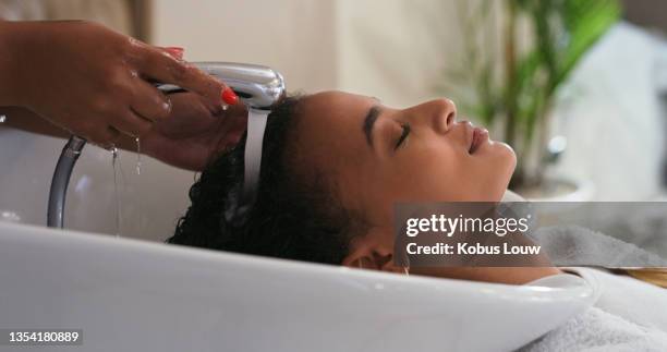 aufnahme einer jungen frau, die sich in einem salon die haare waschen lässt - hair treatment stock-fotos und bilder