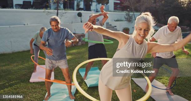 aufnahme einer gruppe von senioren, die mit hoola hoops trainieren - old people sport stock-fotos und bilder