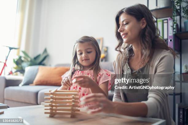 mother and her little girl playing jenga at home - jenga stock pictures, royalty-free photos & images