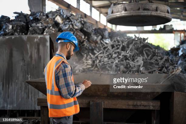 man supervising the scrap magnet at the recycling facility - spare parts stock pictures, royalty-free photos & images