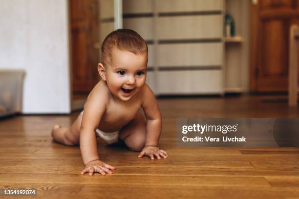 little baby in diaper crawling on floor at home - crawl stockfoto's en -beelden