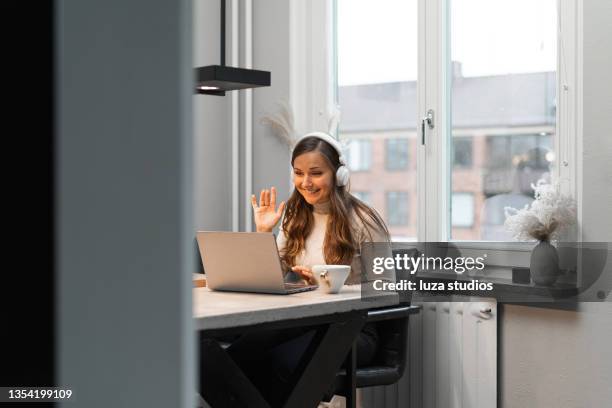 woman greeting her colleagues in a video call - flexible work stockfoto's en -beelden