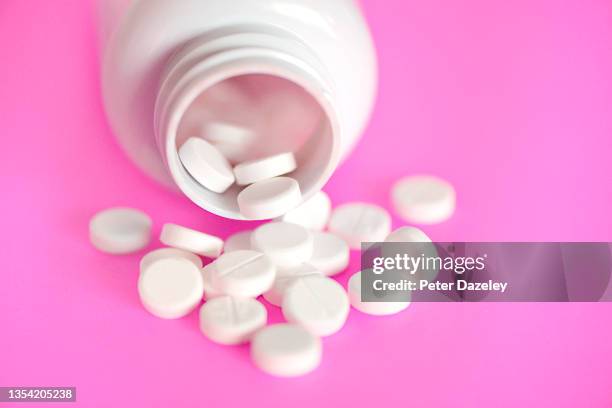 pills on pink background - ibuprofen stock-fotos und bilder