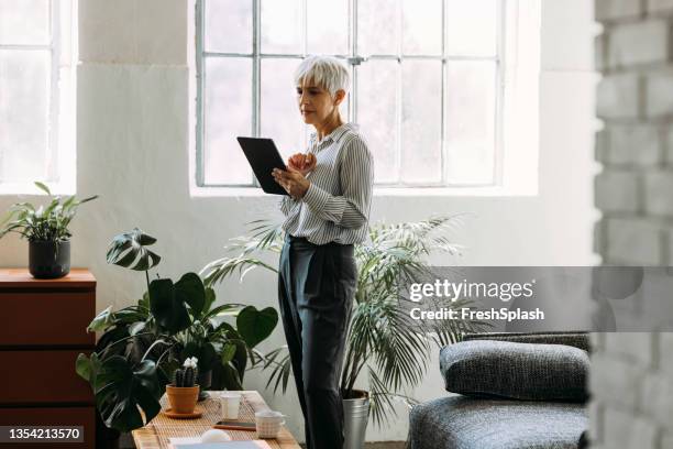 senior woman using digital tablet at home - gray shirt stock pictures, royalty-free photos & images