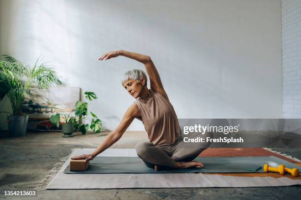 mujer mayor haciendo entrenamiento de entrenamiento en casa - stretching fotografías e imágenes de stock