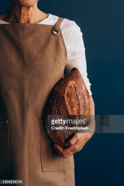 close up photo of woman hand holding freshly made bread - bakery apron stock pictures, royalty-free photos & images