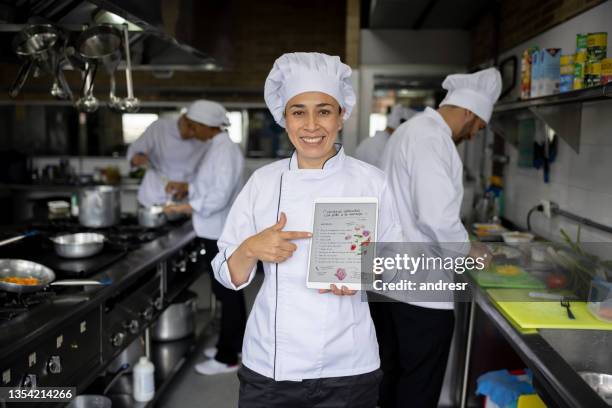 happy chef holding the recipe of a plate on a tablet computer at a restaurant - chef in kitchen bildbanksfoton och bilder