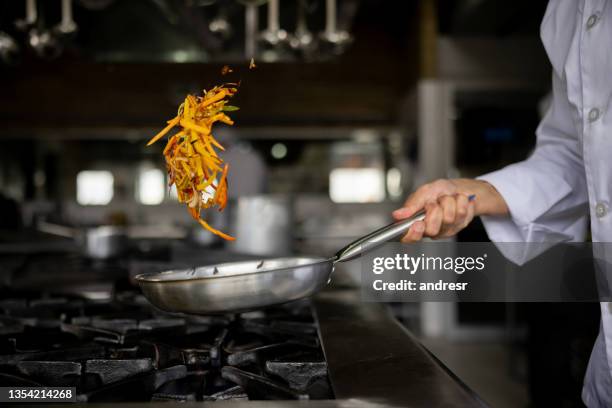 close-up on a chef sauteing vegetables in a pan - roerbakken stockfoto's en -beelden