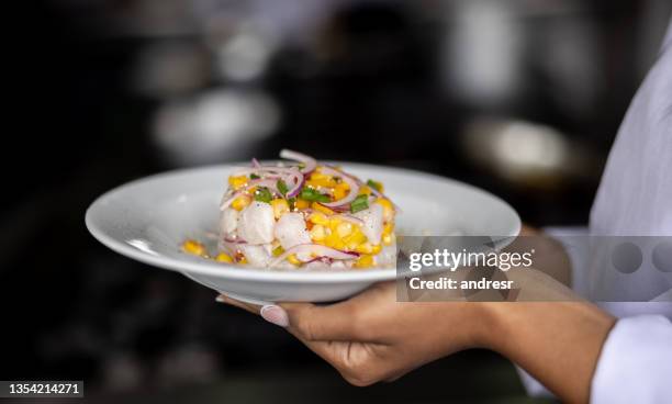 nahaufnahme eines kochs, der einen teller ceviche in einem restaurant hält - dining presentation food stock-fotos und bilder