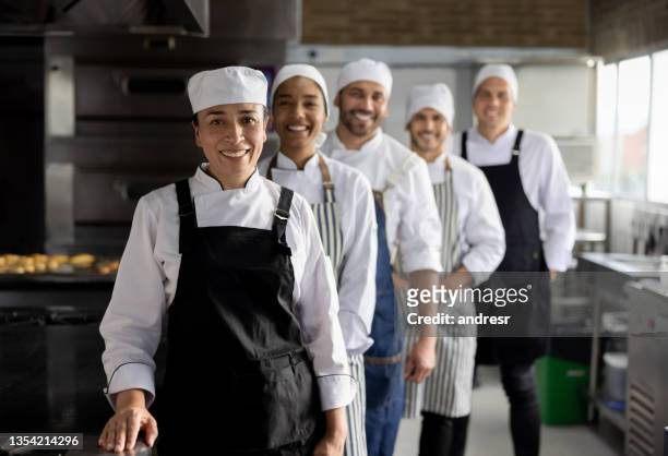 happy group of bakers working at a bakery - essential services employees stock pictures, royalty-free photos & images