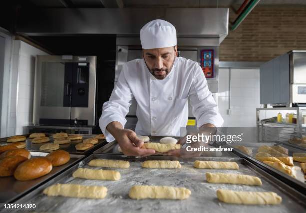 boulanger boulanger cuisant des pâtisseries dans une pâtisserie - boulangerie industrielle photos et images de collection
