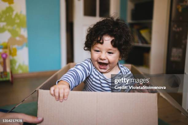 kleiner junge, der während des umzugs in einem pappkarton spielt. - boy in a box stock-fotos und bilder