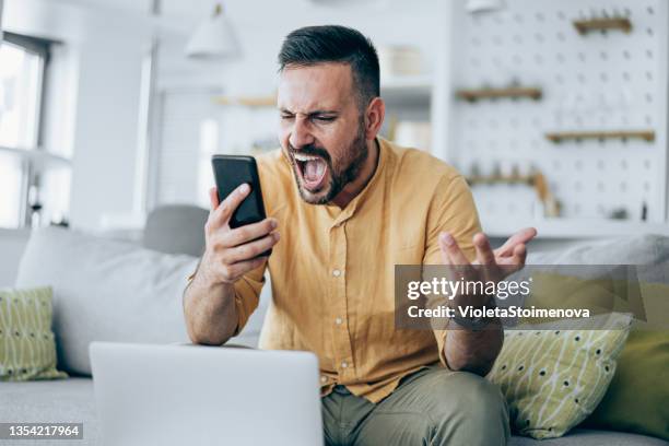 angry businessman talking on his mobile phone at home. - shouting phone stock pictures, royalty-free photos & images