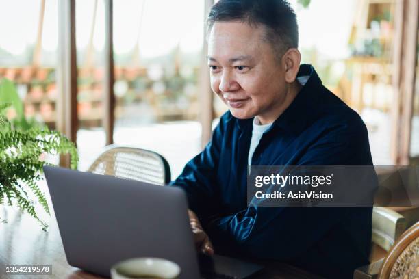 asian active senior man using laptop in the living room at home for e-learning. lifelong learning. elderly and technology - lifelong learning stock pictures, royalty-free photos & images
