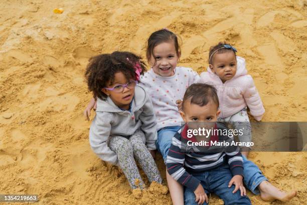 4 children hugging while doing their physiotherapy exercises in the sandpit of the park all happy and smiling - yngre skolåldern bildbanksfoton och bilder