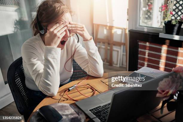 a young woman is tired after a long day of teleworking - gähnen stock-fotos und bilder