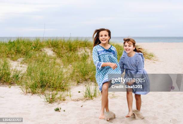 happy girls run on an idyllic beach holding hands, children on vacation - skip stockfoto's en -beelden