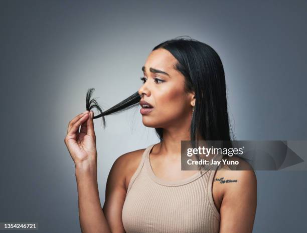 scatto in studio di una bella giovane donna che guarda le sue doppie punte - debolezza foto e immagini stock